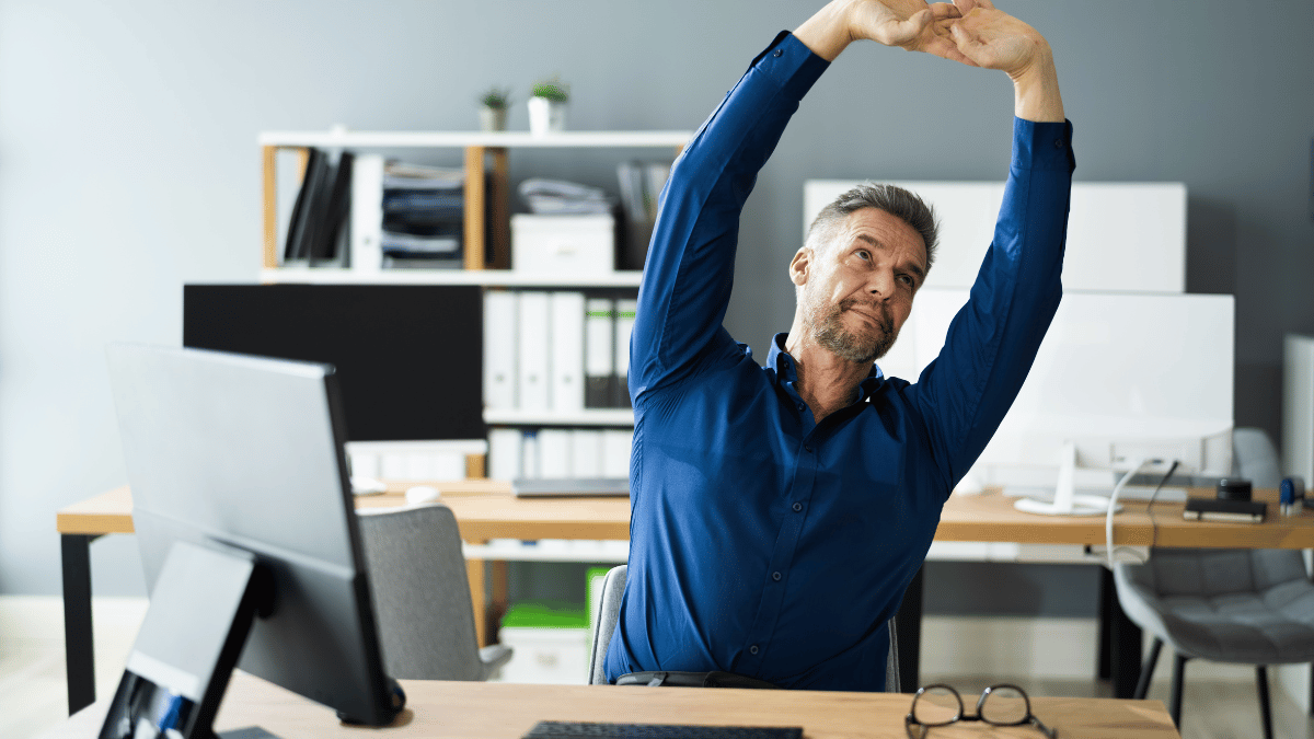 Professionals loosening wrists beside standing desks in open office zone